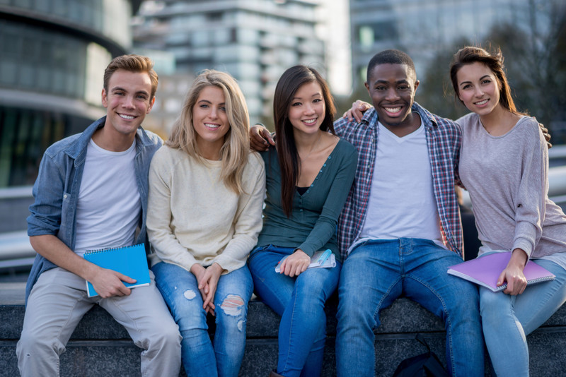 5 young people sitting and smiling